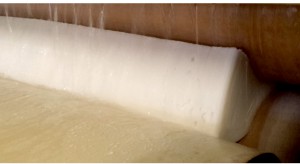 A latex block being rinsed and squeezed during the washing process.